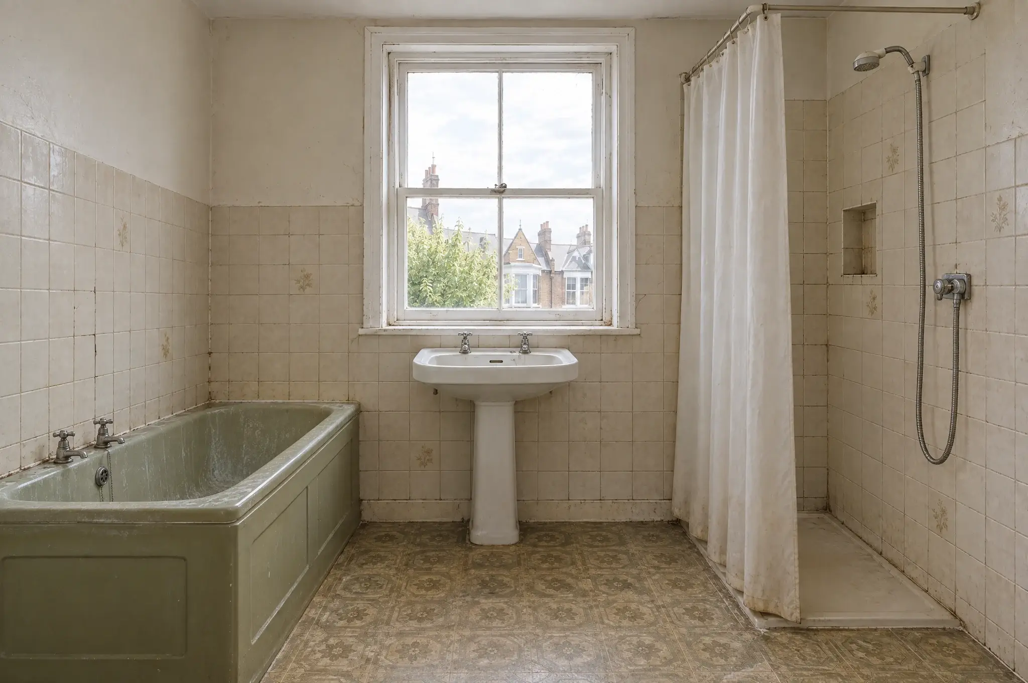 The bathroom before: dated green bath, cracked beige tiles and a shower curtain